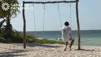 Teenager sitting on a swing facing the sea during a family day trip from Valladolid, Yucatan